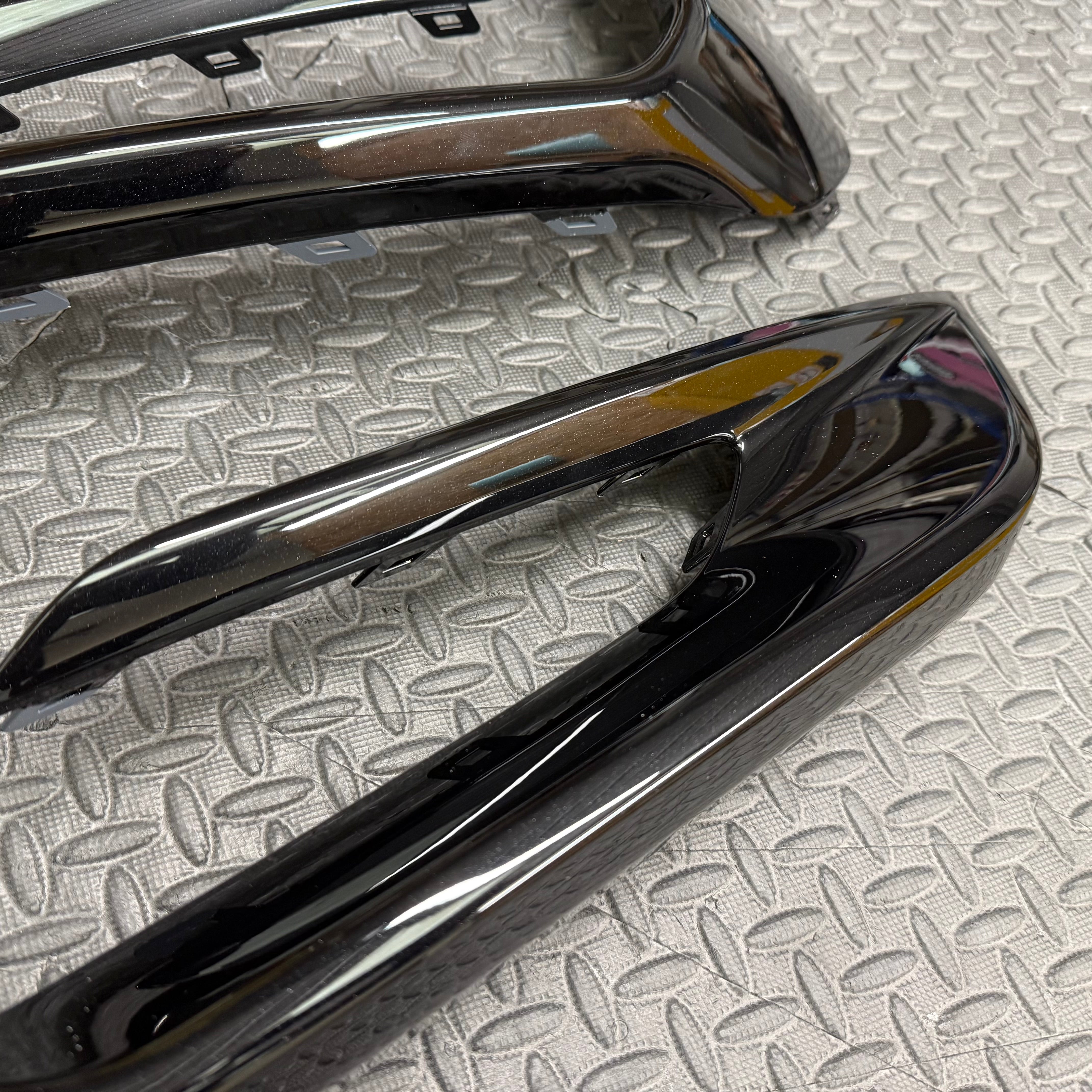 Glossy black car door handles on a textured gray surface