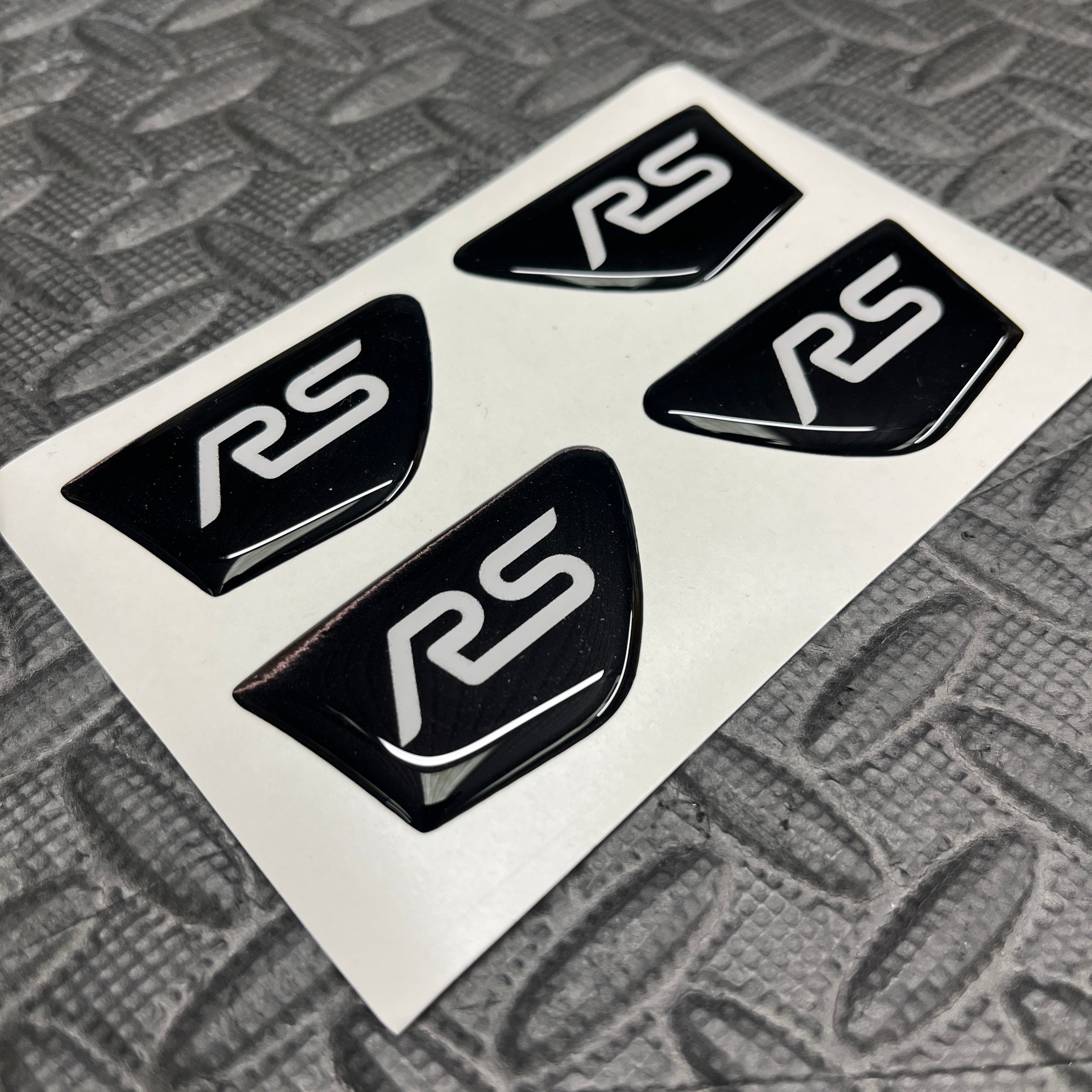 Five black 'RS' logos on a white card with a textured gray background