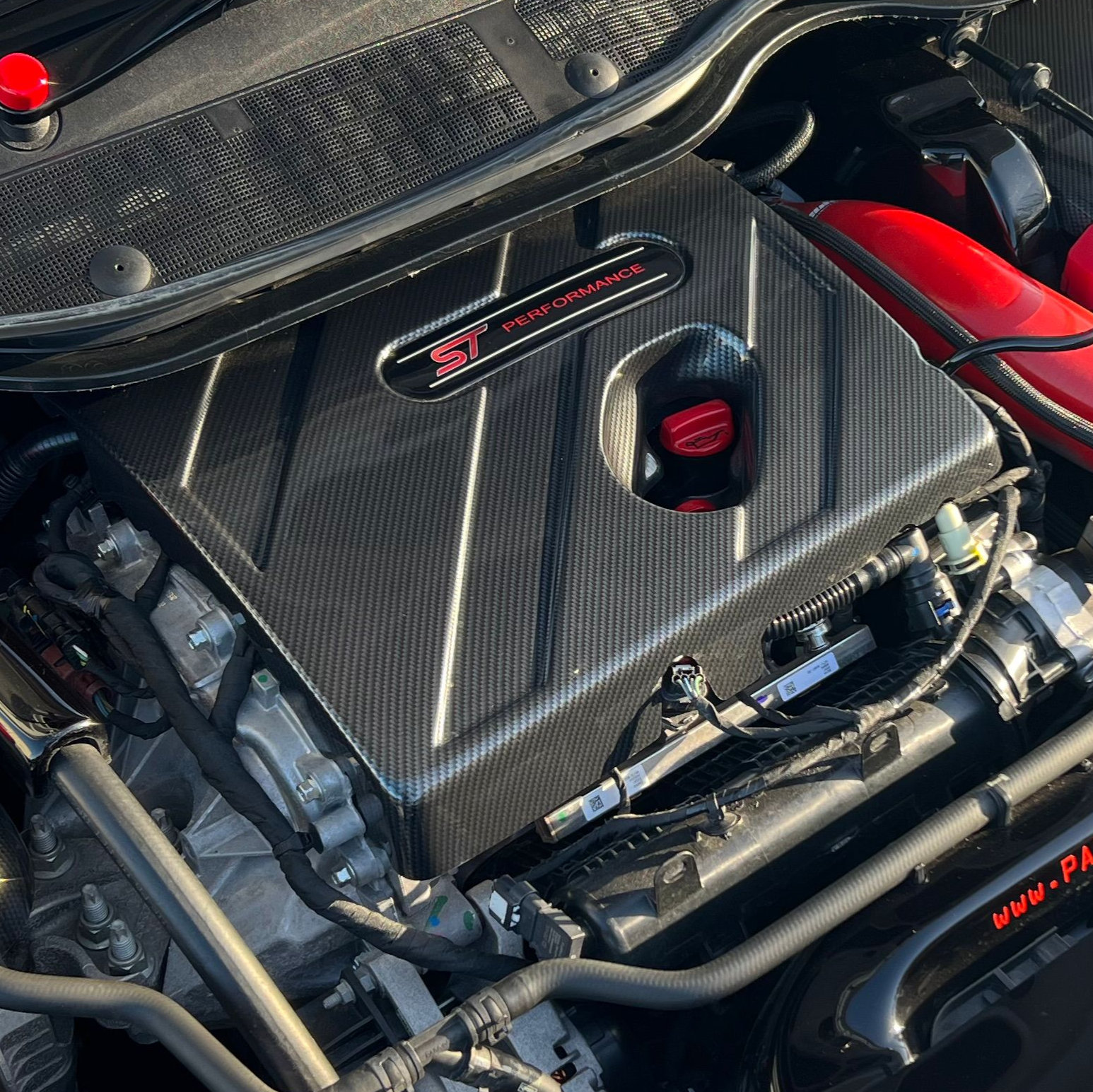 Car engine with 'ST Performance' logo on a carbon fiber cover
