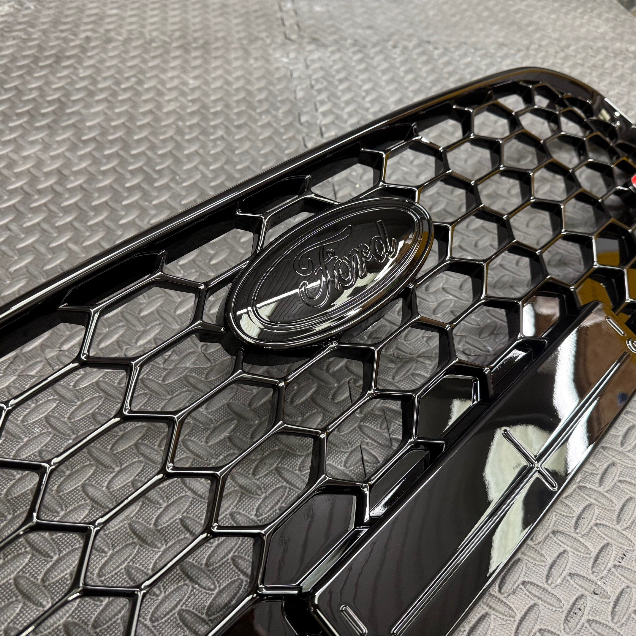 Close-up of a Ford logo on a honeycomb pattern car grille
